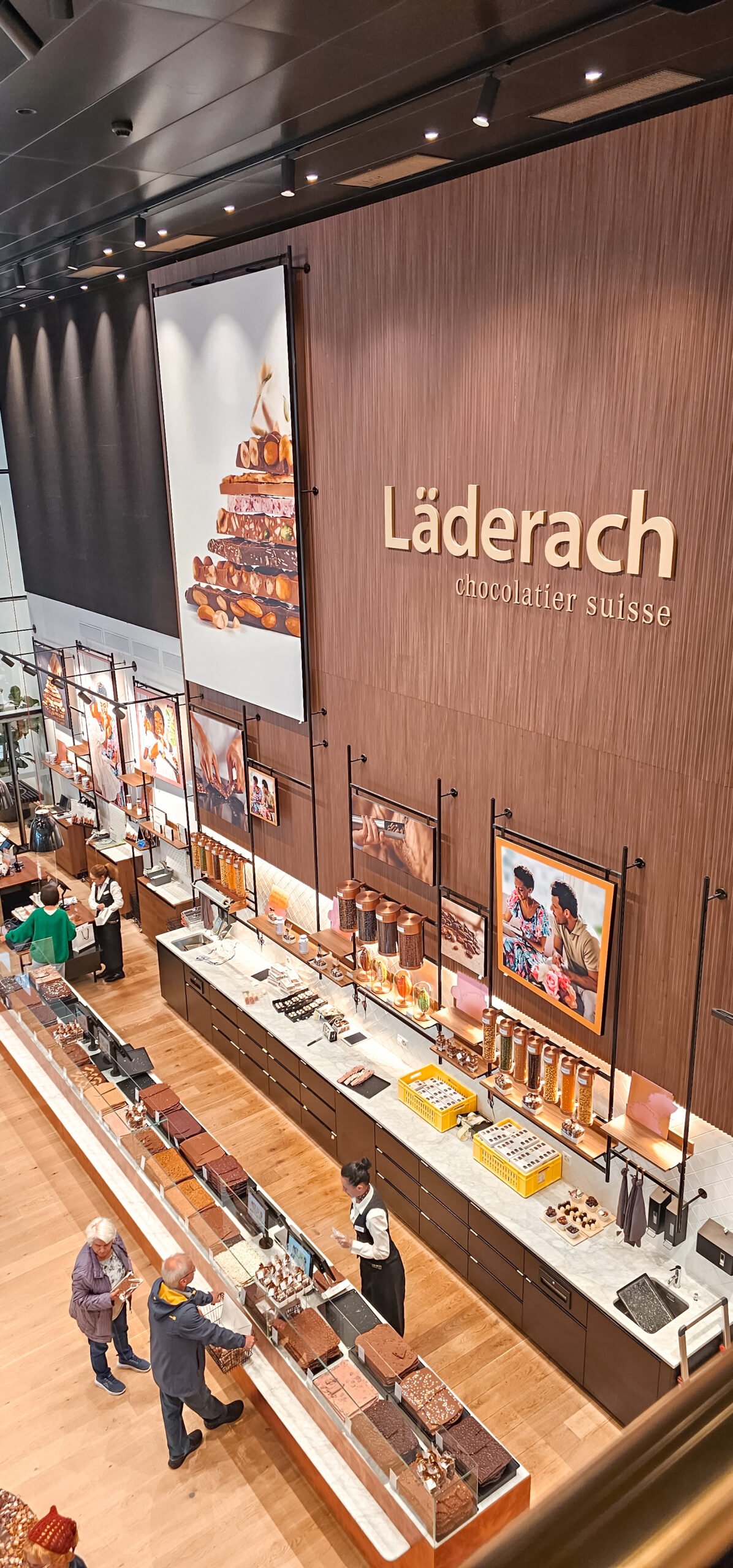 Guia de melhores restaurantes onde comer em Zurique 15 Aceitamos Viagens onde comer em zurique Loja da Läderach, com várias pessoas comprando chocolate.
